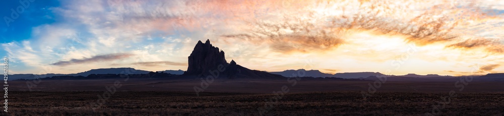 Panoramic American Nature Landscape View of the Dry Desert and Rugged Rocky Mountains. Colorful Sunset Sky Art Render. Taken at Shiprock, New Mexico, United States.