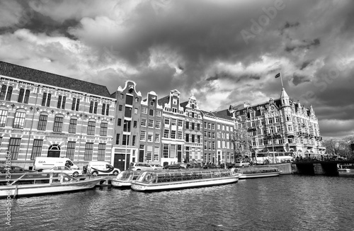AMSTERDAM, THE NETHERLANDS - APRIL 25, 2015: Traditional houses and buildings on the canal with boats on the water
