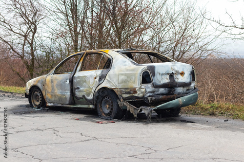 Burned car after an accident on the asphalt road. Side view. Arson of a car, criminal showdowns