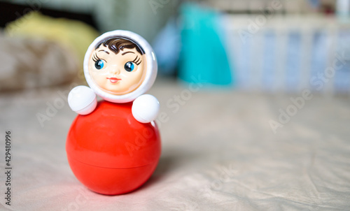 toy tumbler (weeble) red and white is on the bed