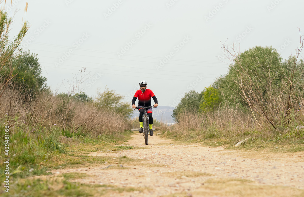 Obraz premium Male cyclist pedaling down a dirt road with a mountain bike. Effort, competition