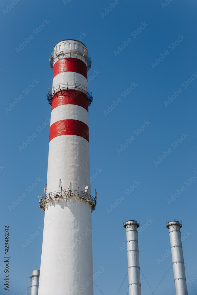 Factory chimney on blue sky. Concept of steam plant, air pollution, heating season Factory chimney on blue sky. Concept of steam plant, air pollution, heating season