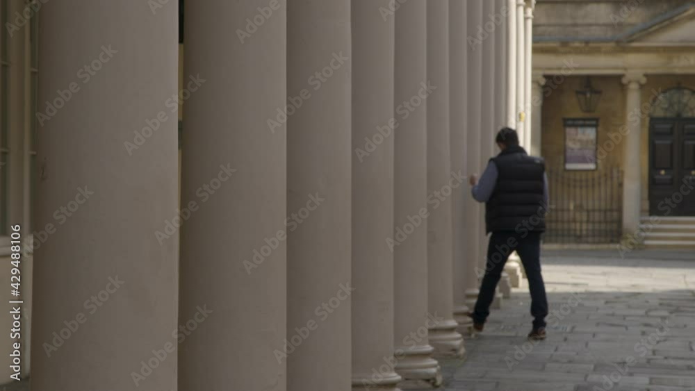 Defocused Shot of Pedestrian Walking Between Old Stone Pillars On Bath Street Defocused Shot of Pedestrian Walking Between Old Stone Pillars On Bath Street