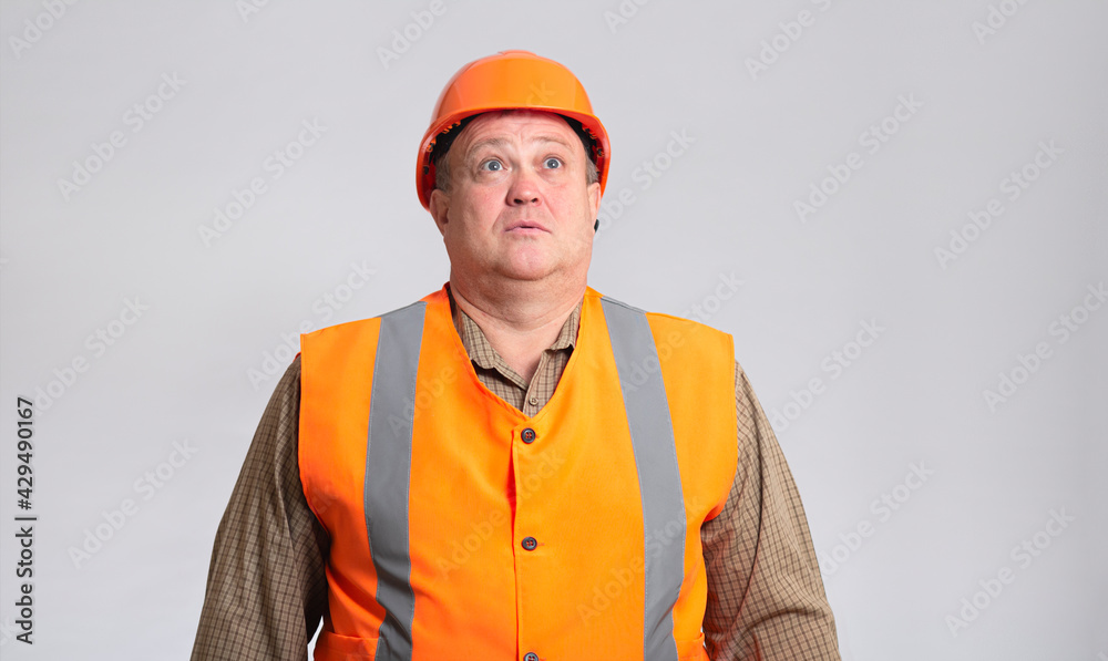 fat construction worker in funny confusion in helmet on grey background, bulder does not understand with humorous face expression fat construction worker in funny confusion in helmet on grey background, bulder does not understand with humorous face expression