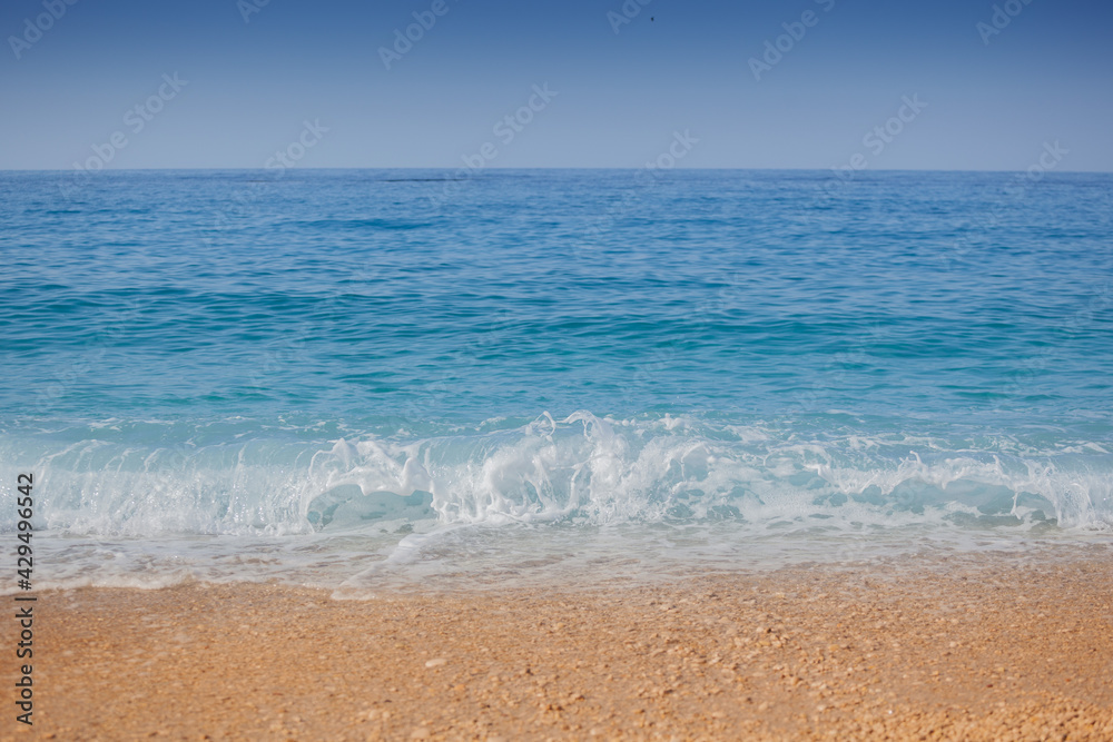 Closeup shoot of calm sea waves and foam on the sand beach.