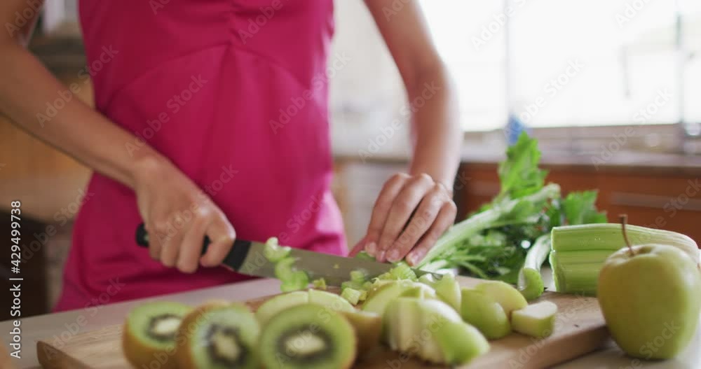 Happy mixed race woman cutting vegetables in kitchen Happy mixed race woman cutting vegetables in kitchen