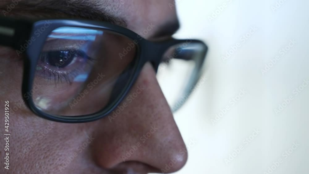 Macro on the eye of a software engineer who is working: the gaze focused on the screen,on the lens of the glasses we see the reflection.Clear and crystal clear image on the right lens. Selective focus Macro on the eye of a software engineer who is working: the gaze focused on the screen,on the lens of the glasses we see the reflection.Clear and crystal clear image on the right lens. Selective focus