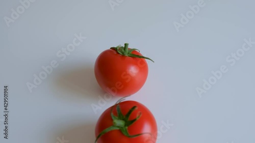 Tomato fruits rolling on white table top.