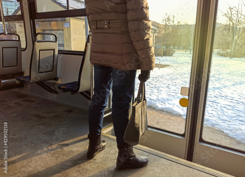 Obraz na płótnie Rear side of a Woman passenger with jeans and coat jacket with hand bag standing in an empty bus during winters. Female traveling and waiting to exit from public transportation at bus station w salonie