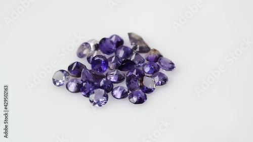 natural violet iolite gemstones on the white background on the turning table photo