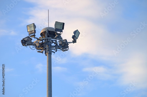 Surrounded spotlight for stadium at the top of tall pole with blue sky background