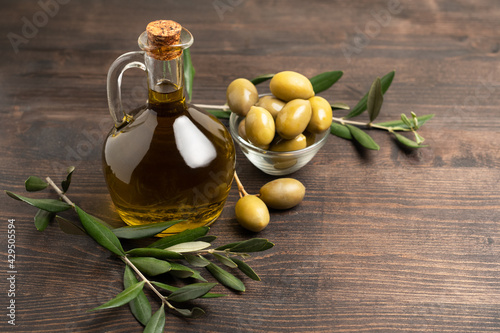 Extra virgin olive oil in a bottle, green olives and olive tree branches. healthy eating concept, basic products of the Mediterranean diet.