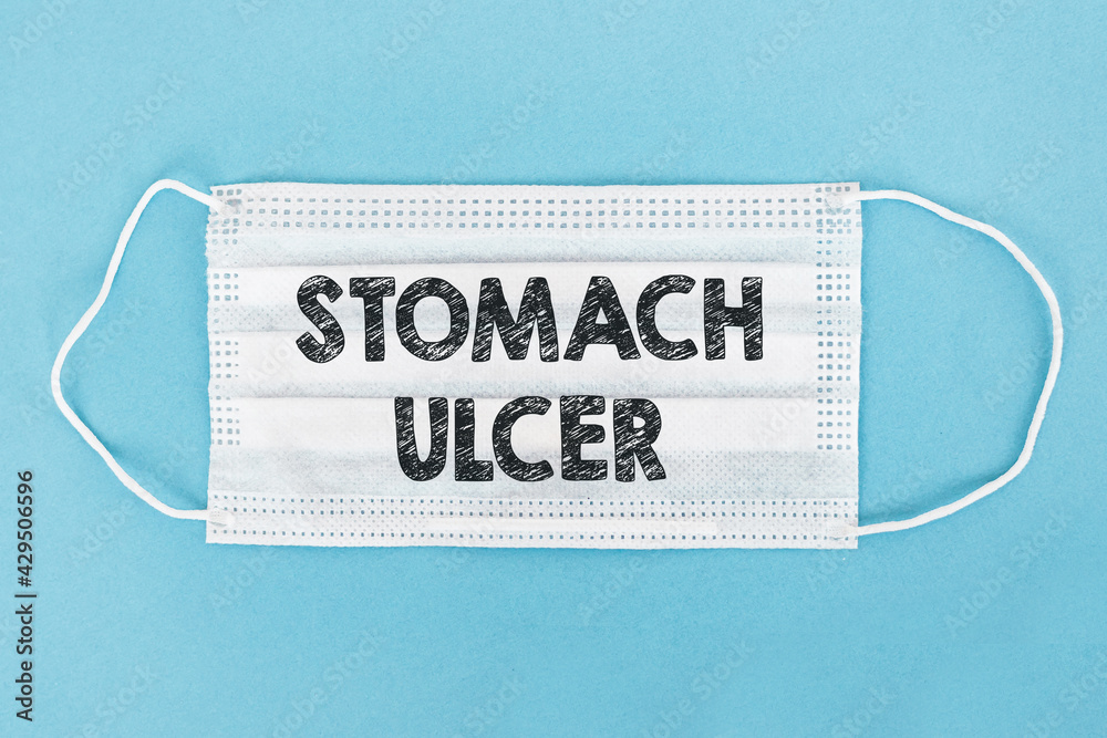 Medical face mask with text STOMACH ULCER on blue background. Medical face mask with text STOMACH ULCER on blue background.