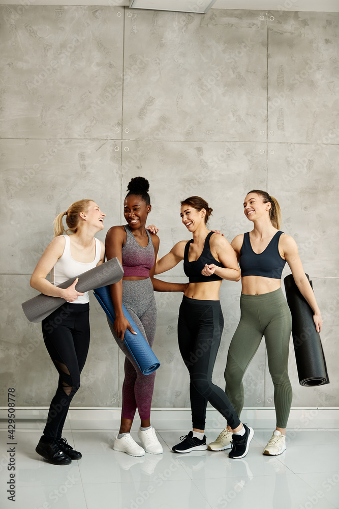 Fototapeta premium Group of diverse athletic women having fun while talking after exercise class at health club.