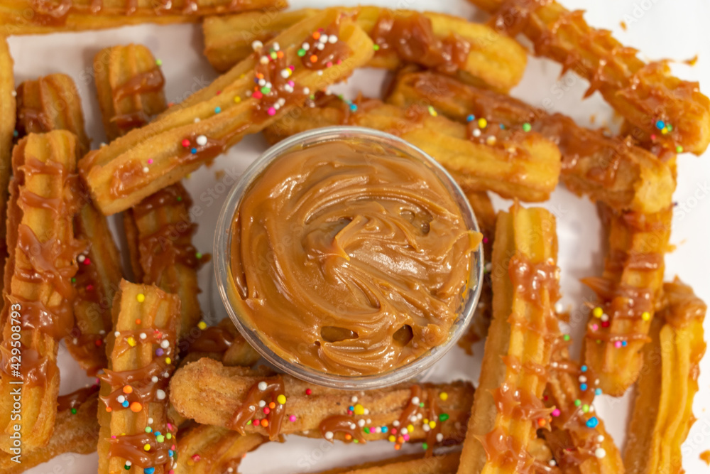 overhead view of typical Spanish churros and container with guava arequipe covered with colored