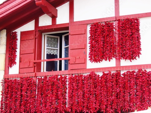 Séchage traditionnel de tresses de piments d'Espelette rouges sur la façade d’une maison du village d’Espelette, dans le pays basque (France) photo