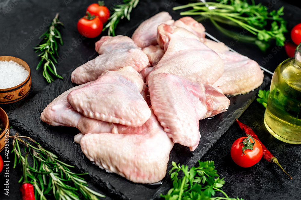 raw chicken wings with spices on a stone background