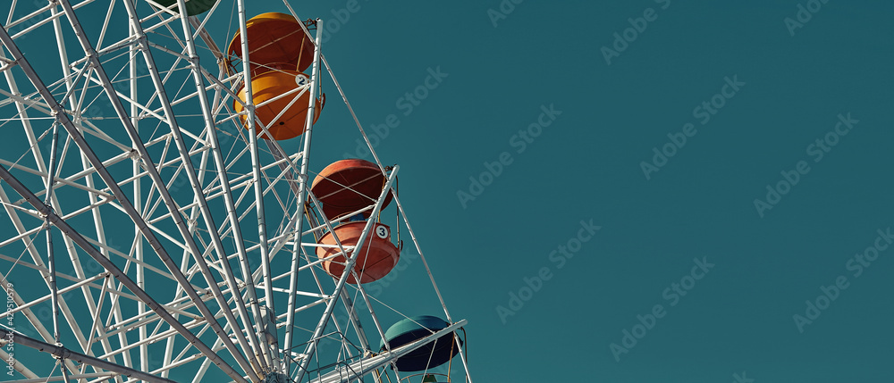 Close-up of the booths of the Ferris wheel attraction against the sky. Empty multi-colored booths with a place to copy the place. An amusement park. Panoramic view Close-up of the booths of the Ferris wheel attraction against the sky. Empty multi-colored booths with a place to copy the place. An amusement park. Panoramic view