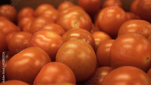 Bright red cherry tomatoes packed together in a cardboard box, makes it look like a sea of red balls. Food processing and shipment concept photo. 