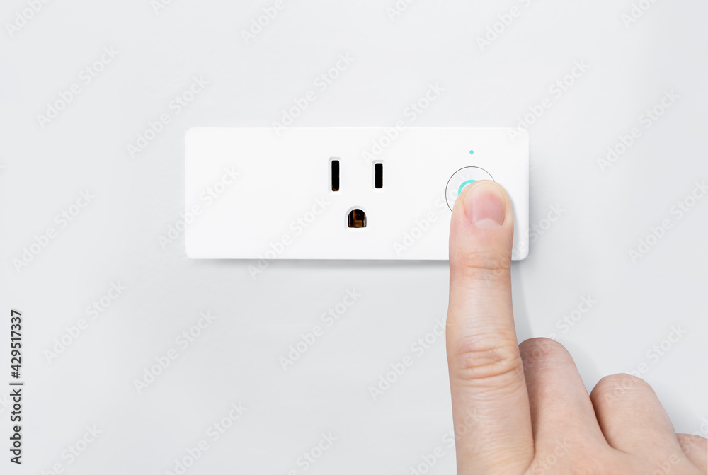 Hand pressing on-off button with blue light active for safety testing electric system on modern smart plug and wifi outlet. Minimal design of electricity with control switch for save energy on a wall. Hand pressing on-off button with blue light active for safety testing electric system on modern smart plug and wifi outlet. Minimal design of electricity with control switch for save energy on a wall.