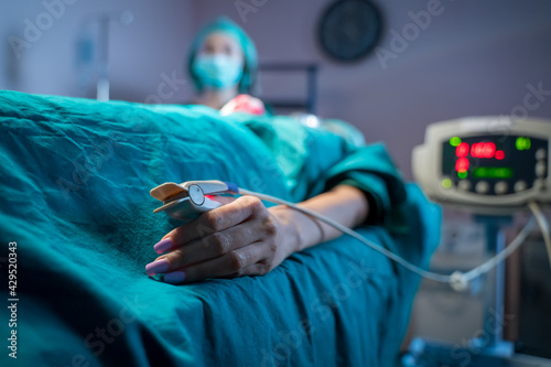 Patient in the operating room,Woman with pulse oximeter after operation monitored by doctor in recovery room of orthopedic clinic. photo