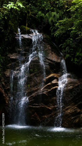 Zooming out on a beautiful natural waterfall found in a tropical forest in Ecuador, South America