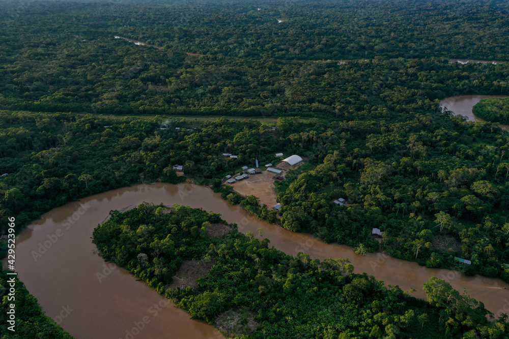 Aerial view of a tropical forest canopy with a tropical river meandering through the rainforest late in the afternoon during sunset