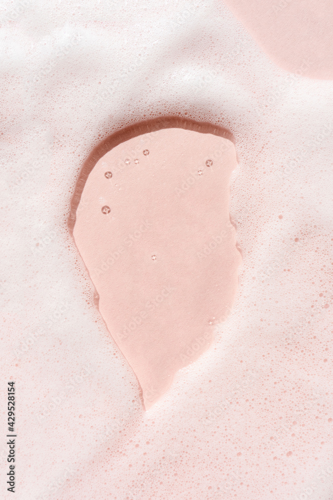 Fototapeta premium The texture of soap foam with bubbles on a pink background.