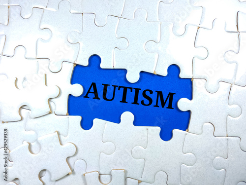 Selective focus.Word AUTISM with jigsaw puzzle on blue background.