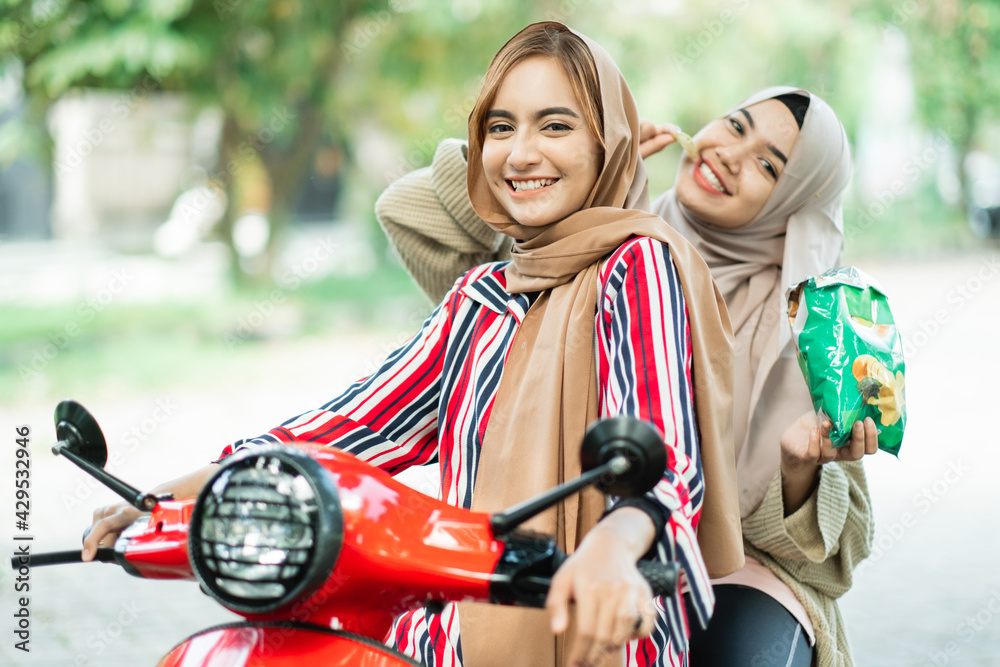 Obraz premium happy muslim friend riding motorcycle scooter together