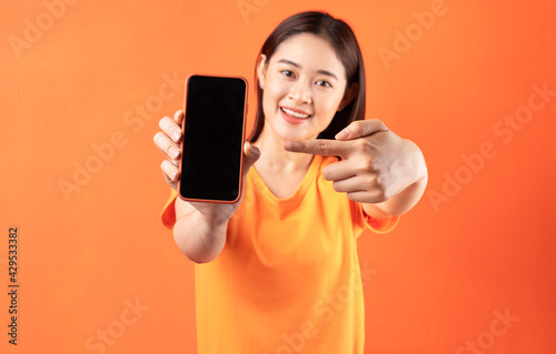 Young Asian woman holding smartphone with empty screen