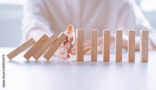 Obraz na plátně Woman's hand stop wooden domino business crisis effect, risk protection concept