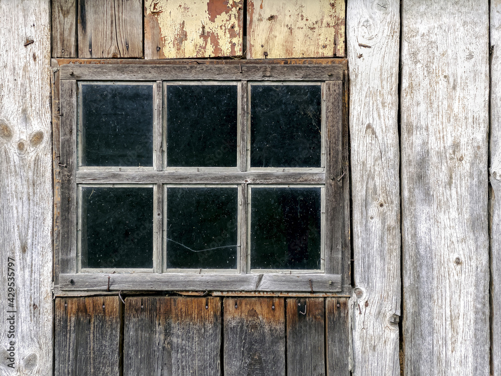 weathered wooden barn wall. old window frame with dirty glass. weathered wooden barn wall. old window frame with dirty glass.