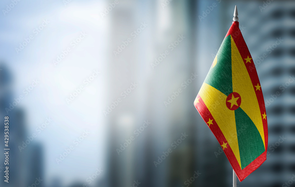 A small flag of Grenada on the background of a blurred background - obrazy, fototapety, plakaty 