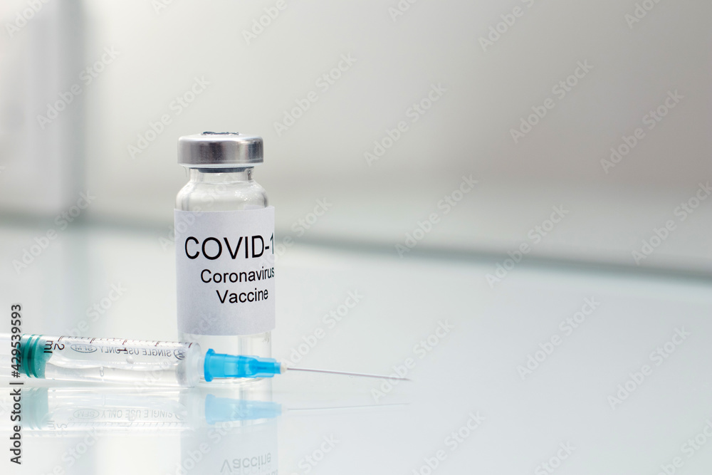 Vial tube with coronavirus vaccine for 2019-nCoV COVID-19 virus and syringe on glass background Vial tube with coronavirus vaccine for 2019-nCoV COVID-19 virus and syringe on glass background