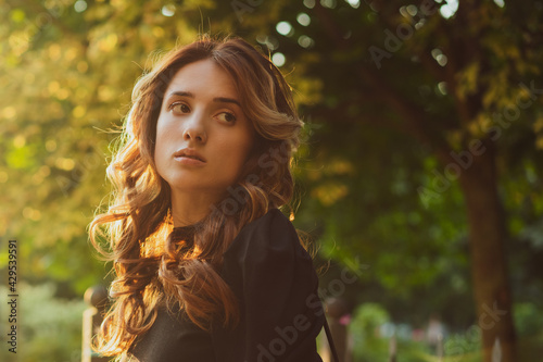 portrait of a beautiful young sad woman at sunset in the sun