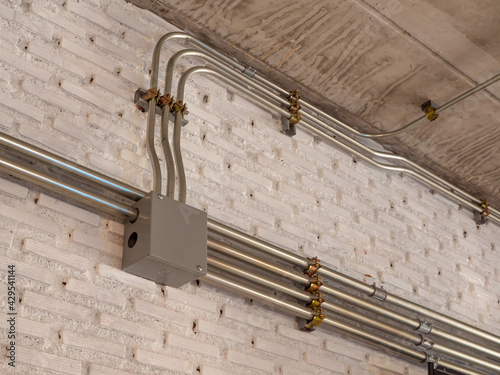 the installation of a electric wire system in the building on white brick wall, electrical conduit work Installation.