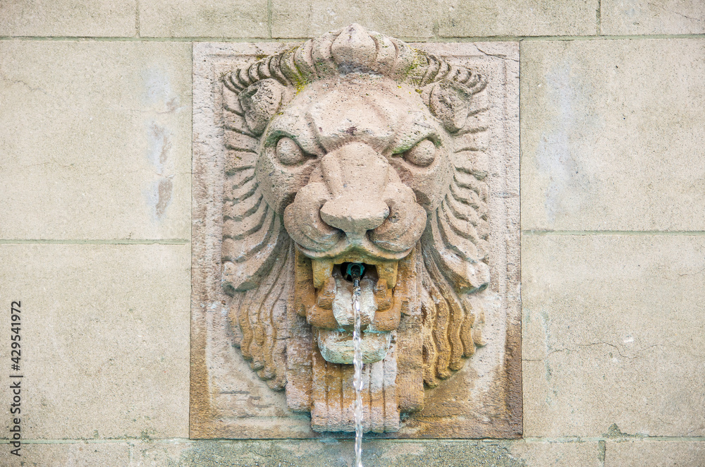 Lion head fountain on concrete wall.