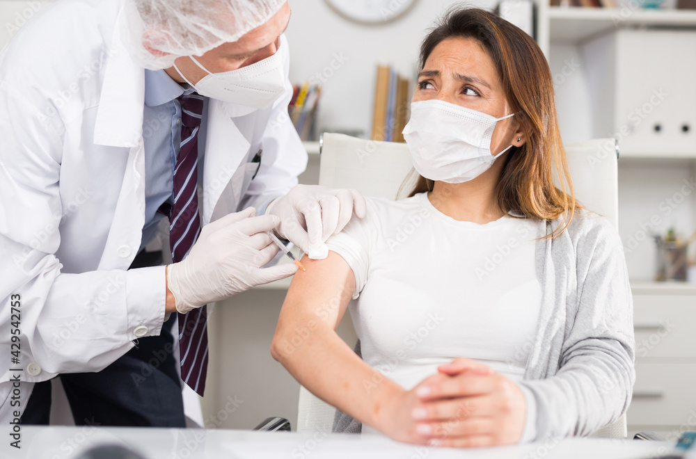 Doctor giving Covid-19 or flu antivirus vaccine shot to patient wear face mask protection at medical office