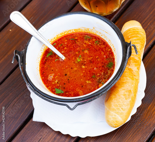 Traditional Mexican tomato soup with bean garnished with fresh greens in serving iron cauldron.. photo