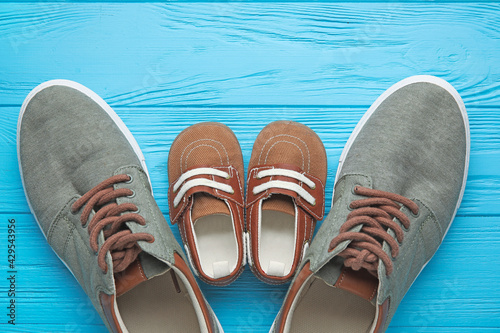 Shoes of father and son on color wooden background © Pixel-Shot