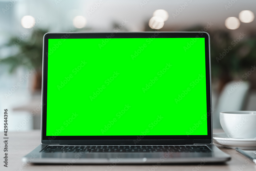 Mockup of laptop computer with empty screen with coffee cup and smartphone on table of the coffee shop background,Green screen Mockup of laptop computer with empty screen with coffee cup and smartphone on table of the coffee shop background,Green screen