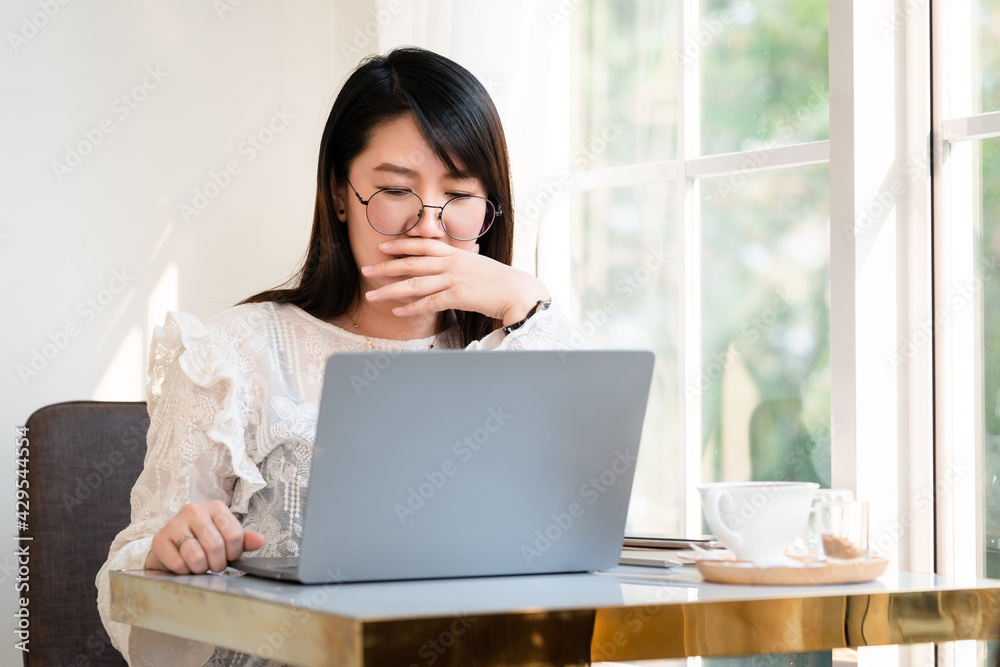 asian freelance business female yawning covering her mouth of courtesy in front of working with laptop computer with coffee cup and smartphone in coffee shop like the background,communication concept asian freelance business female yawning covering her mouth of courtesy in front of working with laptop computer with coffee cup and smartphone in coffee shop like the background,communication concept