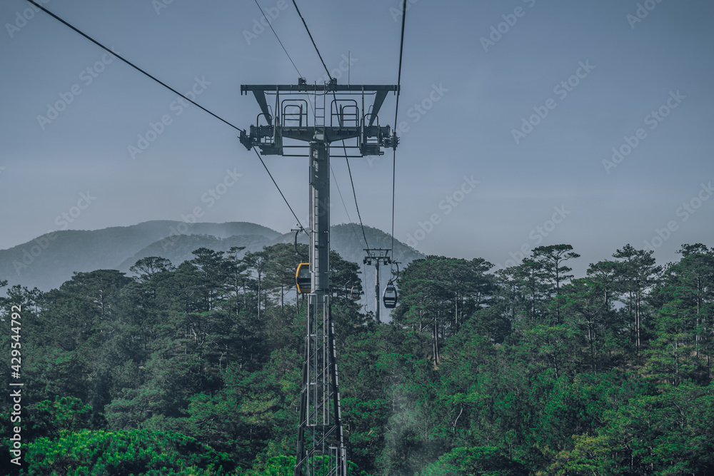 Circulating cable car between Dalat bus station and Robin Hill Truc Lam Vietnam. Close-up view of intermediate support tower. Picturesque landscape view. Pine forest tree tops, mountain. Collection
