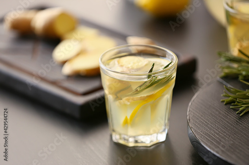 Glass of ginger lemonade and ingredients on dark background, closeup