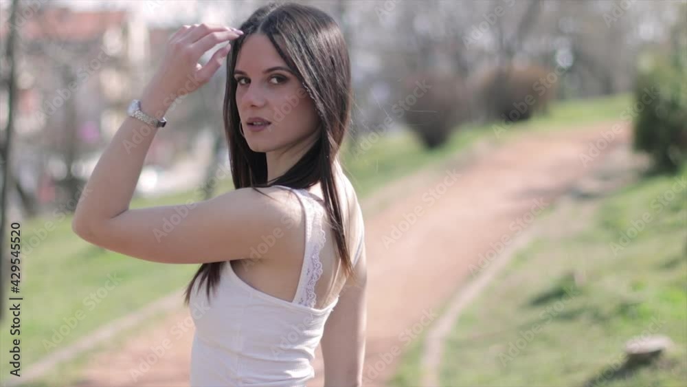 Girl posing for a photo in a park. Young beautiful woman standing in nature. Girl posing for a photo in a park. Young beautiful woman standing in nature.