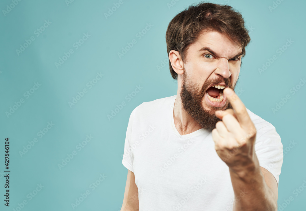 Aggressive man on blue background shows forefinger stress irritability cry Aggressive man on blue background shows forefinger stress irritability cry