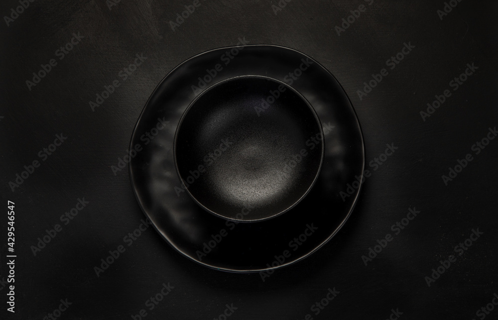 Table setting with a black plates on a black background. Minimalism concept. Table setting with a black plates on a black background. Minimalism concept.
