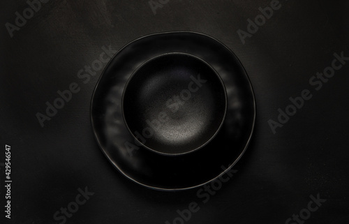 Table setting with a black plates on a black background. Minimalism concept.