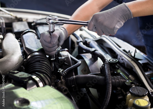 A car mechanic is doing a car repair in a repair shop.